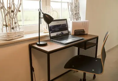 a desk with a laptop and a lamp on it at Villa&Loge in Lontzen