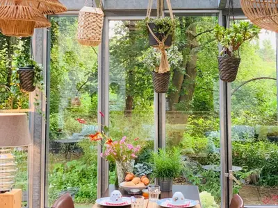 a conservatory with a table and chairs and plants at Hotel Au Nom De Dieu in Dilsen-Stokkem
