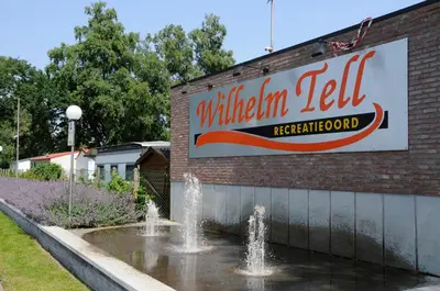 a sign on the side of a building with a fountain at Vakantiepark Wilhelm Tell Vakantieappartement in Oudsbergen
