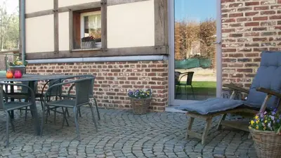 a patio with a table and chairs and a brick wall at 'tMaelhof in Voeren