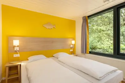 a bedroom with two beds and a yellow wall at Center Parcs Vossemeren in Lommel