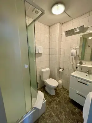 a bathroom with a shower and a toilet and a sink at Hotel Des Ardennes in Verviers