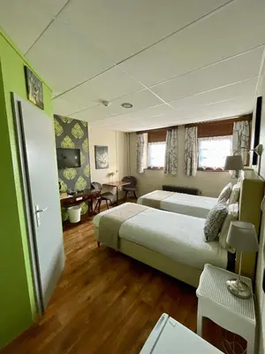 a hotel room with two beds and a table at Hotel Des Ardennes in Verviers