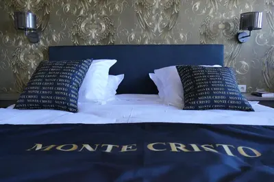 a bed with two black and white pillows on it at Hotel Monte Cristo in Hoeselt