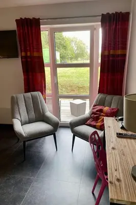a living room with two chairs and a table and a window at Hotel L'Ami du Chambertin in Thimister