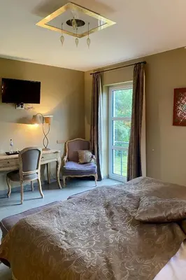a bedroom with a bed and a desk and a window at Hotel L'Ami du Chambertin in Thimister