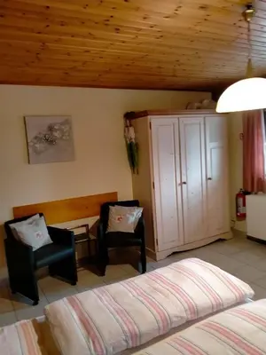 a bedroom with a bed and a chair and a cabinet at gasthof lederhose in Diepenbeek