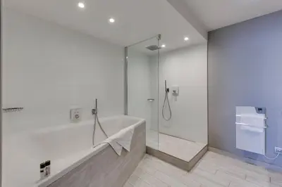a white bathroom with a tub and a shower at Van der Valk Hotel Liège Congres in Liège