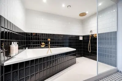 a bathroom with a tub and black tiles at Van der Valk Hotel Liège Congres in Liège