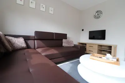 a living room with a brown couch and a tv at Stefjes Holiday Home in Dilsen-Stokkem
