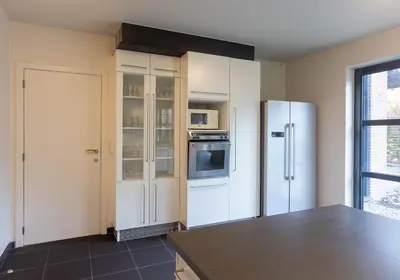 a kitchen with white cabinets and a refrigerator at Vakantiehuis Piantho in Overpelt