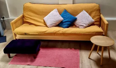 a yellow couch with pillows on it with a pink rug at Staying with the artist in Teuven