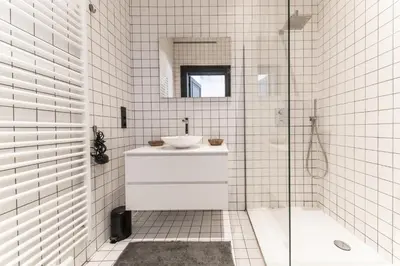 a white tiled bathroom with a sink and a shower at Appartement Guillemins Station Terrace in Liège