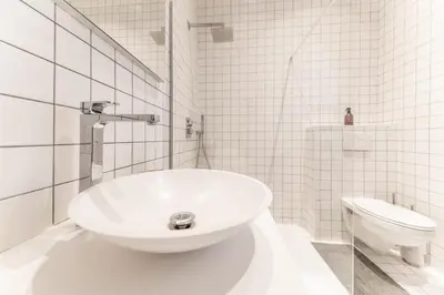 a white bathroom with a sink and a toilet at Appartement Guillemins Station Terrace in Liège