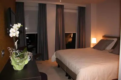 a bedroom with a bed and a vase of flowers on a table at B&B de Taller-Hoeve in Maasmechelen