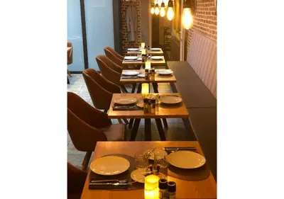 a row of wooden tables in a restaurant with chairs at Boutique Hotel Caelus VII in Tongeren