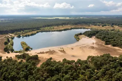 an aerial view of a lake in the woods at Hotel De Vossemeren by Center Parcs in Lommel