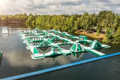 a row of green and white boats in the water at Hotel De Vossemeren by Center Parcs in Lommel