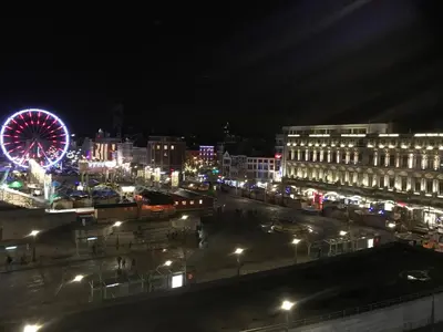 a city lit up at night with a ferris wheel at Studio des princes in Liège