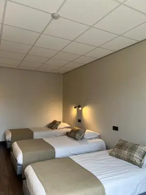 a room with three beds and a ceiling at Hotel De Venne in Genk