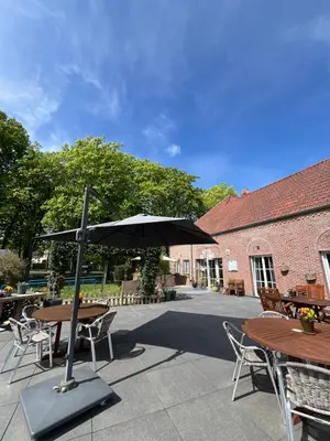 a patio with tables and chairs and an umbrella at Hotel De Venne in Genk
