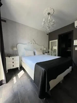 a bedroom with a large white bed and a chandelier at L'écrin des Vennes - Liège centre in Liège