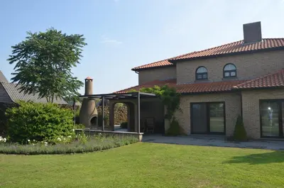 a house with a patio and a grass yard at B&B Serenity in Pelt