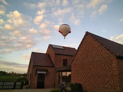 a hot air balloon flying over a brick house at Vakantiewoning Mierzicht - privé wellness - Haspengouw 6p in Boekhout