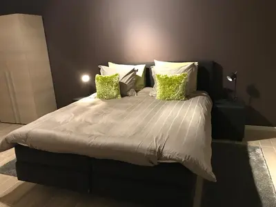 a bedroom with a large bed with green pillows at Wijndomein Zwaeneberg in Voeren
