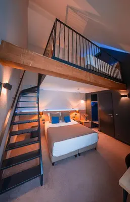 a bedroom with a bed and a spiral staircase at Hotel Neuvice in Liège