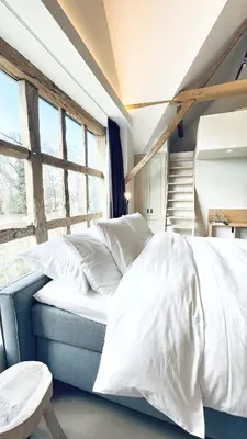 a bedroom with a bed with white sheets and a window at Winning De Zwaen in Hasselt