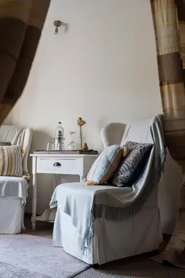 a living room with a chair with pillows on it at B&B Hof van Vervoering in Voeren