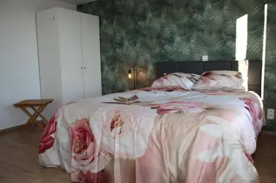 a bedroom with a large bed with pink and white sheets at Juwel Fruithof in Zepperen