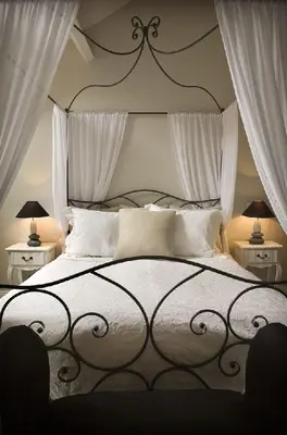 a bedroom with a large bed with white curtains at Auberge 's Gravenhof in Voeren