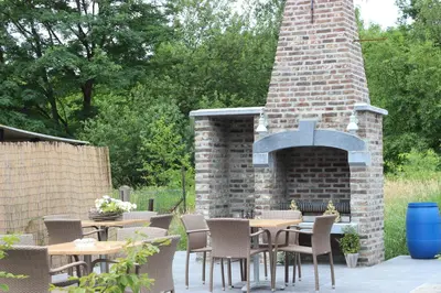 an outdoor patio with tables and chairs and a brick oven at B&B Don Genaro in Dilsen-Stokkem