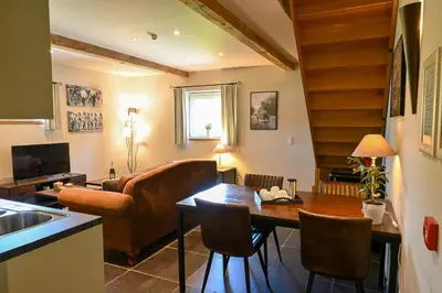 a kitchen and living room with a table and a couch at Wellness B&B De Zevenslaper in Geetbets