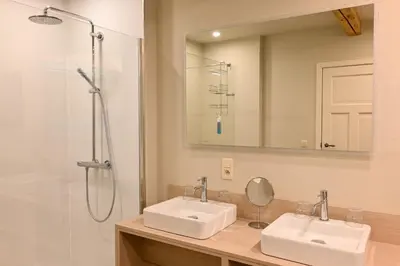 a bathroom with two sinks and a shower at Wellness B&B De Zevenslaper in Geetbets