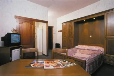 a room with a bed and a table with a tv at Hotel IL Castellino in Chaudfontaine