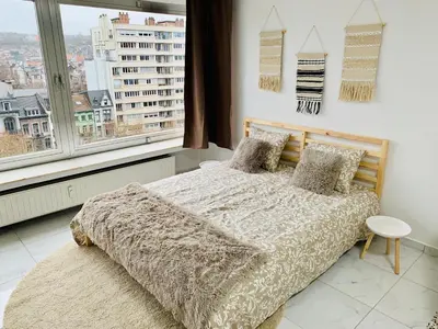 a bedroom with a bed and a large window at Le Cocon d'Avroy in Liège