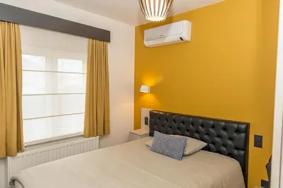 a bedroom with a bed and a yellow wall at Belrom Hotel in Sint-Truiden
