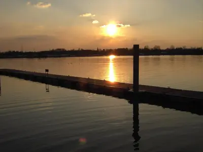 a sunset over a body of water with a dock at Botel Ophoven in Kinrooi
