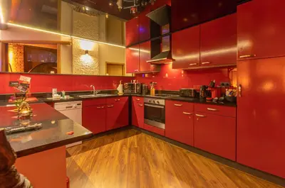 a kitchen with red cabinets and wooden floors at Le Baiser de Shogun in Ensival