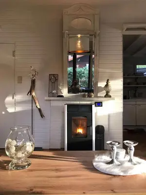 a kitchen with a fireplace and a table with a vase at Chalet Sint Barbara in Zutendaal