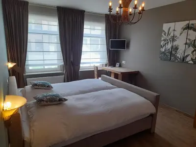 a bedroom with two beds and a chandelier at B&B De Floreffe in Overpelt