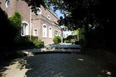 a brick building with a brick road in front of it at B&B Het Agnetenklooster in Maaseik