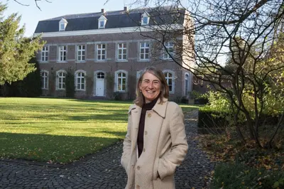 a woman is standing in front of a building at B&B Het Agnetenklooster in Maaseik