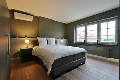 a bedroom with a large bed and two windows at AMADIS in Kesselt