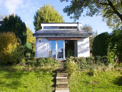 a small white building in the middle of a garden at Holiday Home in Gemmenich with Forest Views in Ten Eiken