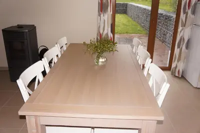 a wooden table with white chairs and a vase with flowers at Holiday home La ferme brabant in Voeren