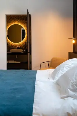 a bedroom with a white bed and a mirror at Designhotel Beila in Bilzen